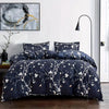 A dark blue duvet cover set with a white floral pattern displayed on a bed.