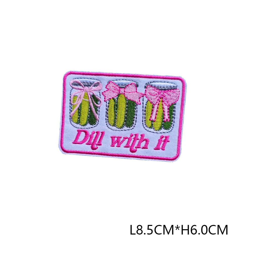 Pink embroidered letter patch with a pink bow and green fruit design