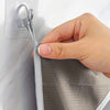 A hand is opening a gray wall-mounted laundry storage bag with multiple pockets.