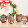 Three wooden kalimba thumb pianos shaped like cats with metal keys displayed on a light surface.