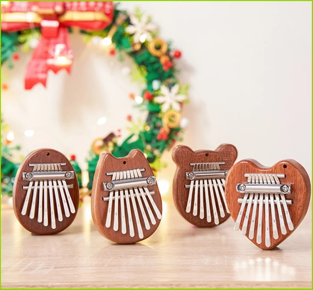 Three wooden kalimba thumb pianos shaped like cats with metal keys displayed on a light surface.