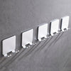 A row of white aluminum wall-mounted adhesive razor holders mounted on a gray wall.