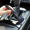 A hand is holding a black soft bristle interior detailing brush over the console of a vehicle.