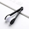 A black portable microfiber glasses cleaning cloth with a brush is shown resting on a piece of paper.