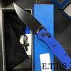 A folding pocket knife with a black drop point blade and a blue handle is shown next to its sheath.