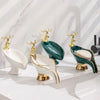 A set of leaf-shaped ceramic soap dishes with gold accents and deer heads on a white marble surface.