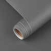 Roll of self-adhesive matte white vinyl wallpaper shown rolled up on a gray surface.