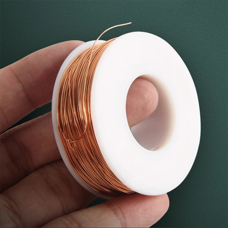 A hand holds a roll of bare copper wire with multiple diameters, showing the coiled metal strands and white plastic spool.