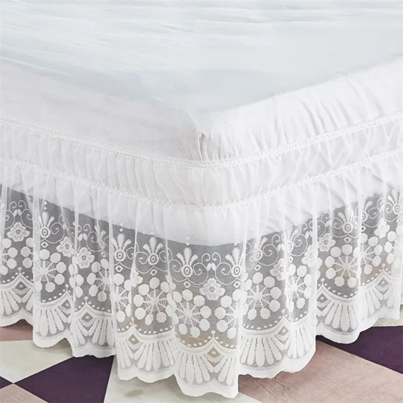 White ruffled lace bed skirt with elastic fit displayed on a bed.