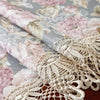 A close-up of a pink and gray floral jacquard lace table runner with delicate white embroidery.