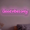A glowing pink neon sign with the text Good vibes only mounted on a wall.
