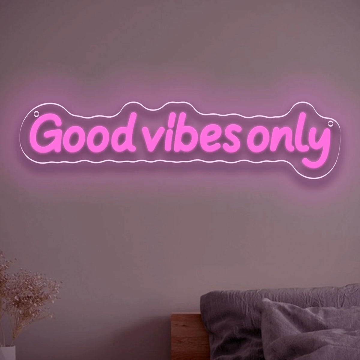 A glowing pink neon sign with the text Good vibes only mounted on a wall.