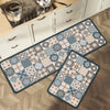 A rectangular floor mat with a patterned design is placed on a wooden floor next to kitchen cabinets.