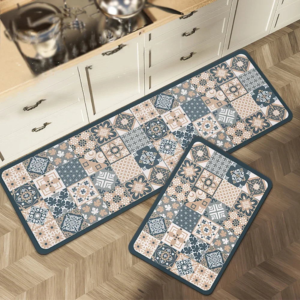 A rectangular floor mat with a patterned design is placed on a wooden floor next to kitchen cabinets.