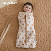 A baby wearing a beige breathable cotton sleep sack with a subtle floral pattern, lying on a woven fabric background.
