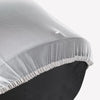 A close-up of a sheer white mosquito net cover with a gathered edge, positioned over a dark fabric.