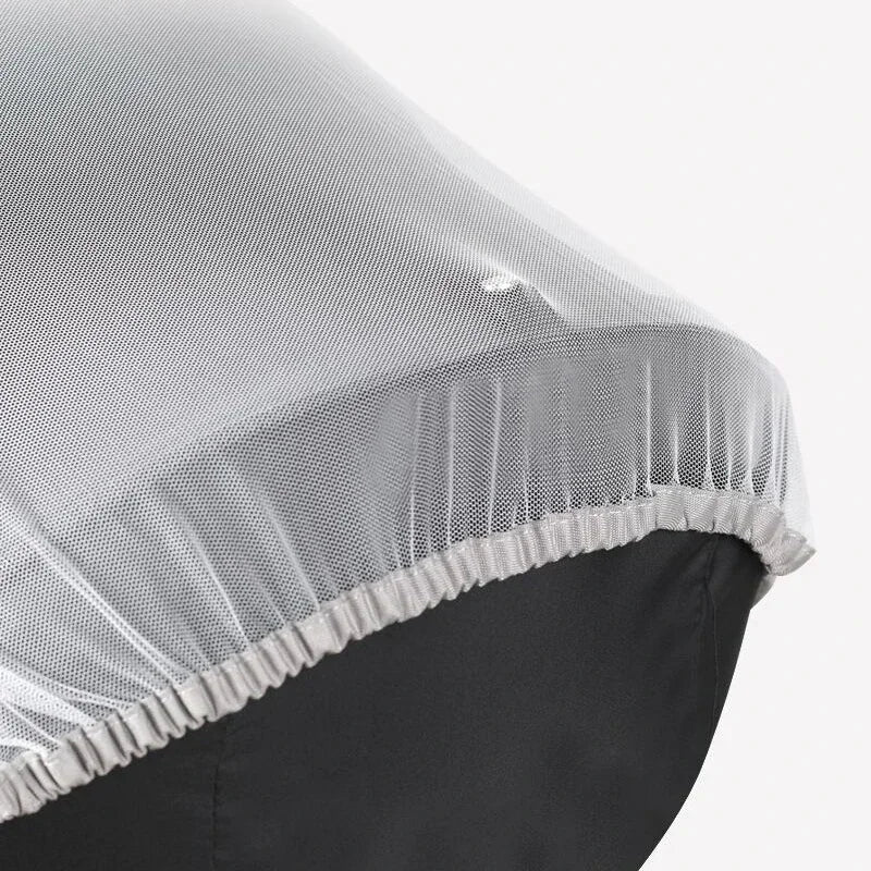 A close-up of a sheer white mosquito net cover with a gathered edge, positioned over a dark fabric.
