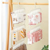 A wooden clothes rack displaying various colored baby clothes and garments hanging on clip hangers.