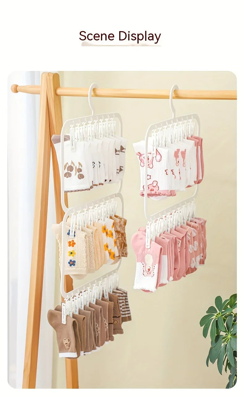 A wooden clothes rack displaying various colored baby clothes and garments hanging on clip hangers.