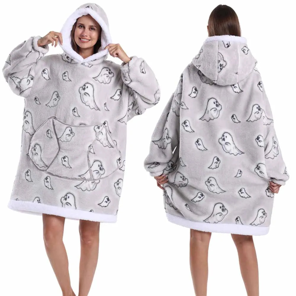 Eine Frau modelliert einen grauen, lappigen, oversized Fleece-Hoodie mit Kapuze und einem Muster aus kleinen Vogelgrafiken.