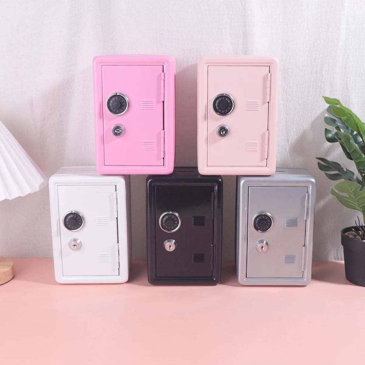 A set of five vintage metal piggy banks with combination locks in pink, beige, white, and black colors.