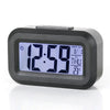 A black compact LED digital alarm clock displaying 12:59, with a display showing the date and temperature.