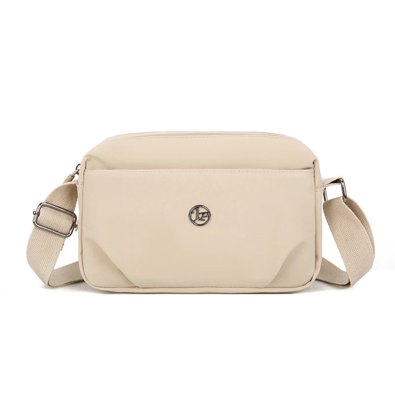 A beige lightweight water-resistant nylon crossbody bag with a flap closure and adjustable strap.