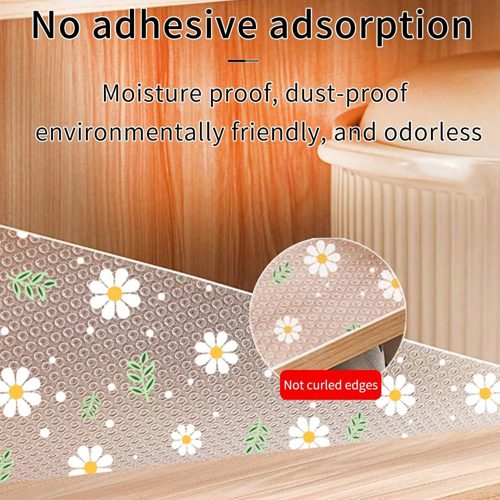 A beige kitchen drawer mat with a white daisy flower pattern is shown on a wooden surface.