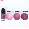 A set of plum-colored liquid candle dye in dropper bottles showing 1, 5, and 10 drops on a pink surface.
