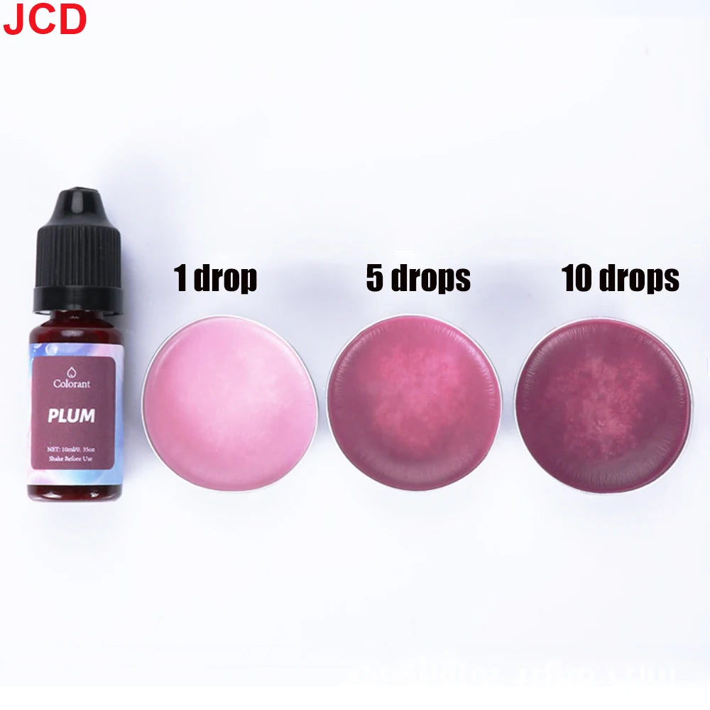 A set of plum-colored liquid candle dye in dropper bottles showing 1, 5, and 10 drops on a pink surface.