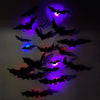 A collection of black bat silhouettes illuminated by purple and pink LED lights on a wall.