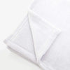A white fluffy flannel throw blanket folded and displayed on a light surface.
