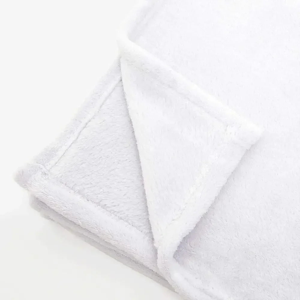 A white fluffy flannel throw blanket folded and displayed on a light surface.