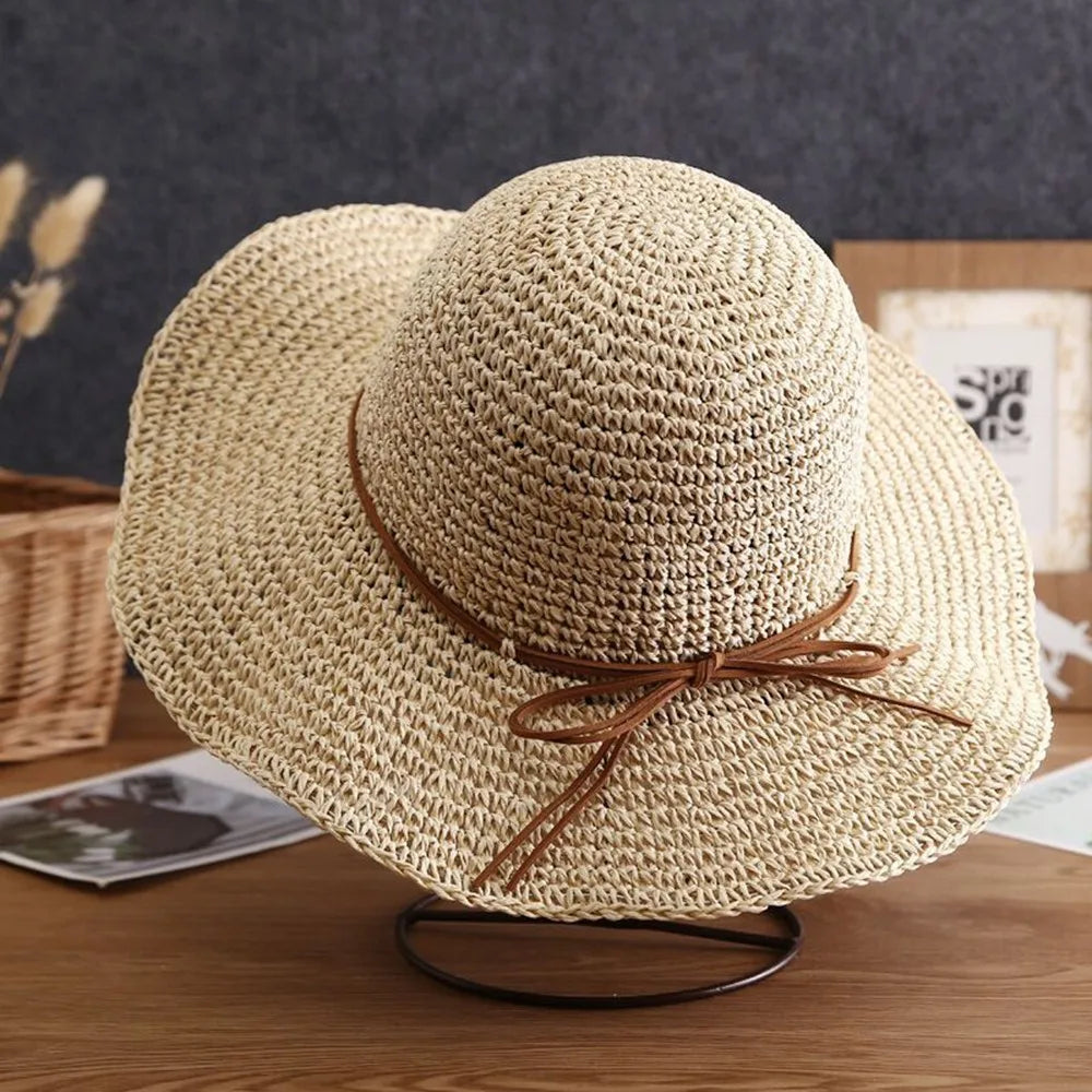 Sombrero de paja beige de ala ancha con textura tejida sobre una superficie de madera.