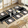 A set of waterproof geometric table runners and placemats featuring black and silver patterns on a wooden table.
