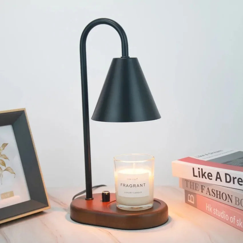 A black electric candle warmer lamp with a wooden base and glass holder on a white surface.