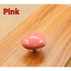 Pink heart-shaped toilet flush button resting on a wooden surface.