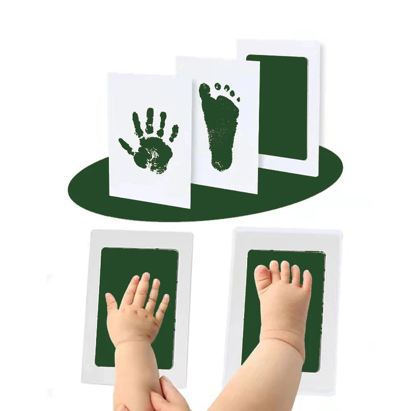 A kit containing white cards with green hand and foot imprints, shown next to a baby's hand and foot.