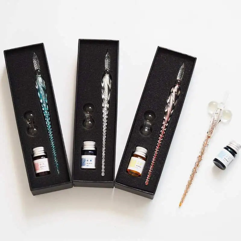 Un set de plumas de inmersión de cristal con tinta dorada, exhibidas en portavasos negros.