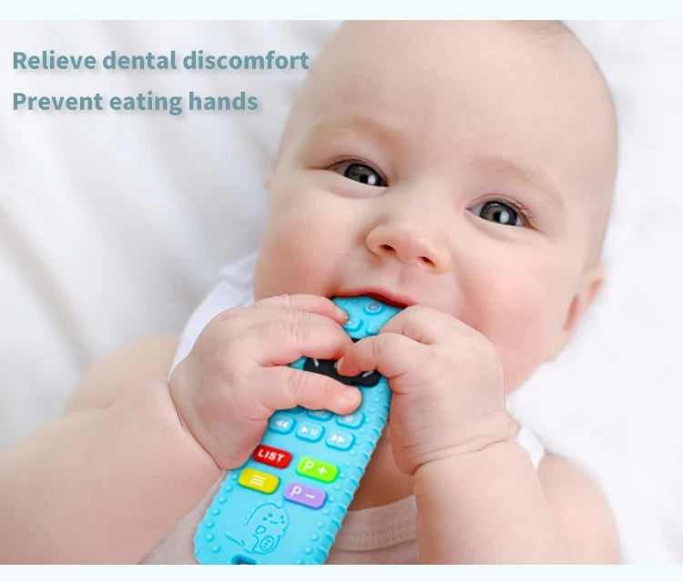 A baby is holding a blue silicone teether toy with a remote control shape to relieve dental discomfort.