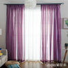Purple sheer voile curtains with a rod pocket hanging in front of a bright window.