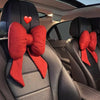 Red butterfly bow tie neck pillow with a red fabric cover shown inside a car seat.