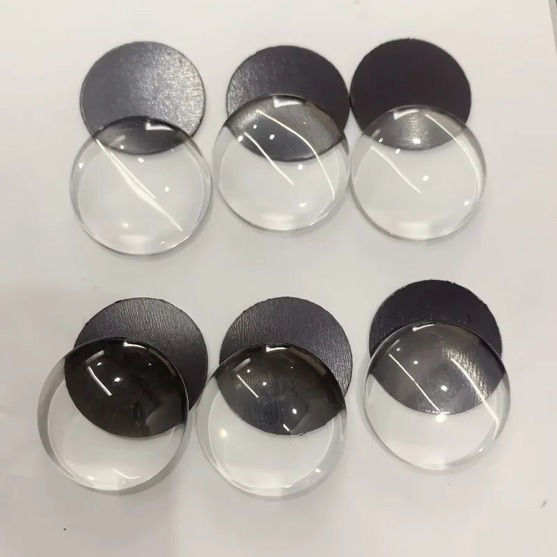 A collection of clear glass domes and dark gray magnets arranged in a row.