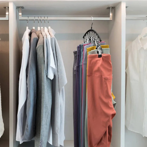 A rack of various colored pants and socks hanging on a multi-clip hanger in a closet.
