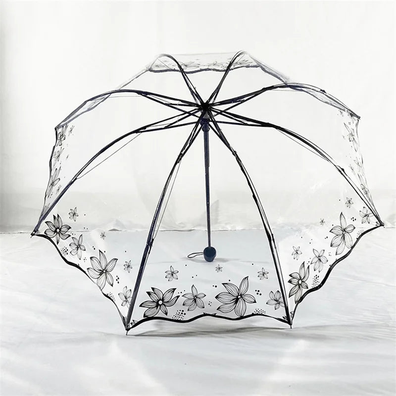 A clear, retro transparent arch umbrella with a black frame and delicate floral design resting on white bedding.