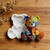 A colorful crochet texture teddy bear silicone mold resting on a wooden surface.