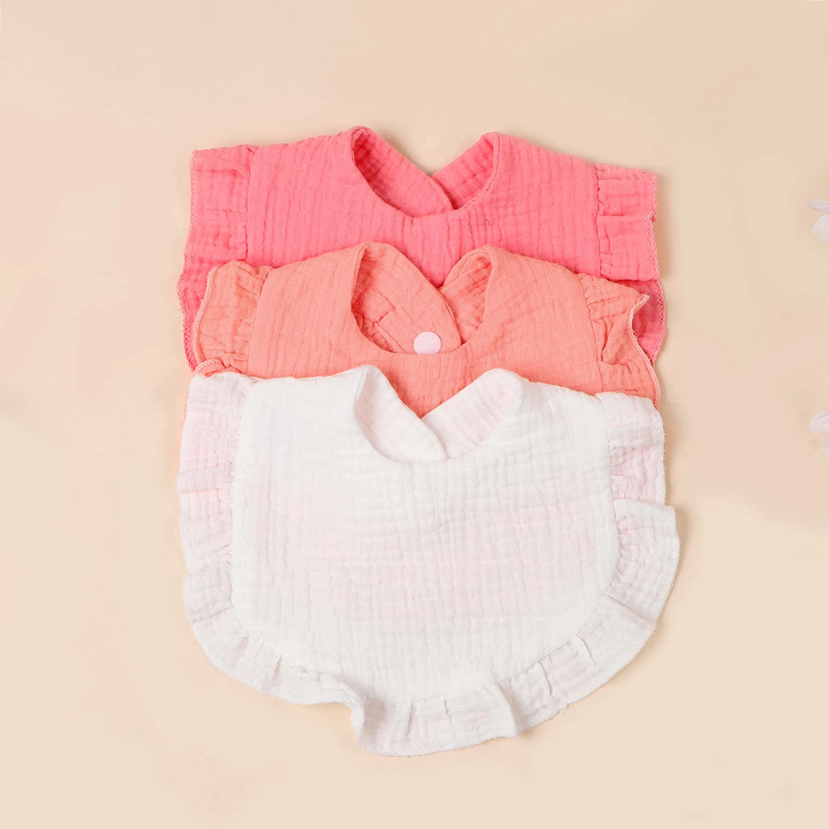 A set of three soft cotton ruffle bibs in pink and white for babies.