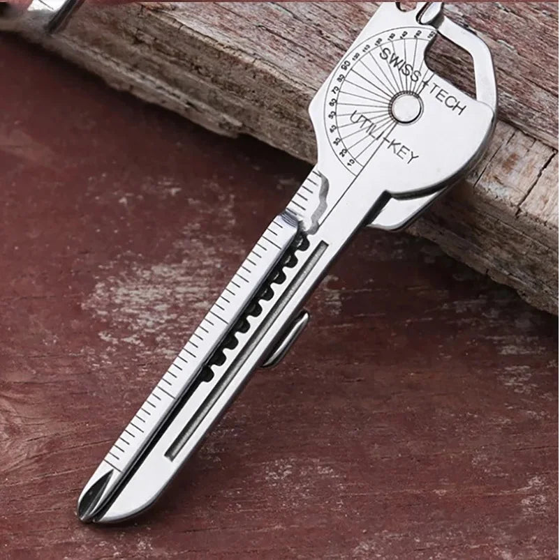 Silver SwissTech multi-tool keychain with a serrated blade and various tools resting on a wooden surface.