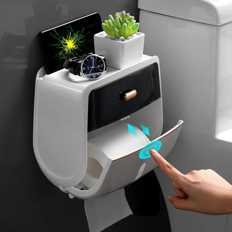 Una mano interactúa con un portar rollos de papel higiénico impermeable montado en la pared, con un reloj negro y una planta 