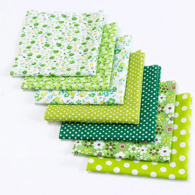 A bundle of green and white floral dot patterned cotton fabric squares for patchwork and quilting.